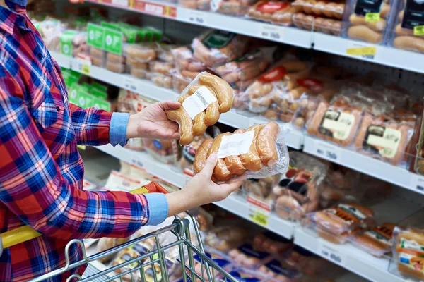 Woman chooses sausages in store — Stock Photo, Image