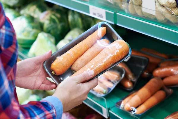 El comprador selecciona la zanahoria en la tienda — Foto de Stock