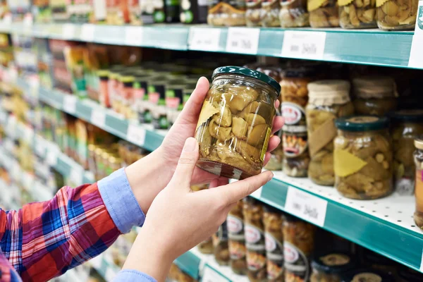 Vrouw koopt gezouten paddestoelen in winkel — Stockfoto