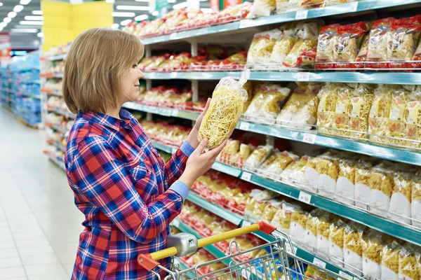 Vrouw met pakket pasta in winkel — Stockfoto