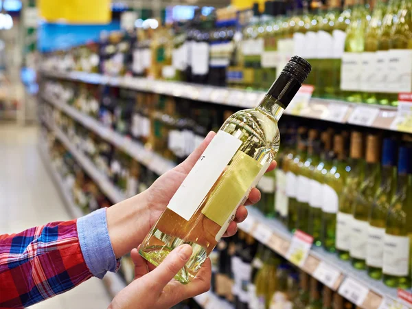 Woman with bottle of white wine in store — Stock Photo, Image