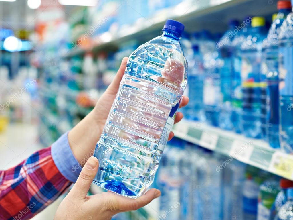 Buyer with bottle drinking water in shop — Stock Photo © ryzhov 104834984