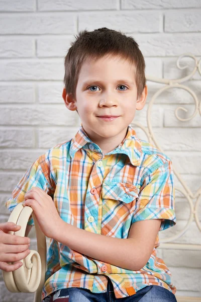 Handsome boy is sitting on ancient bench in studio — Stock Photo, Image