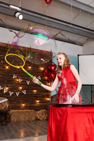 Chica en vestido rojo hace grandes burbujas de jabón — Foto de Stock