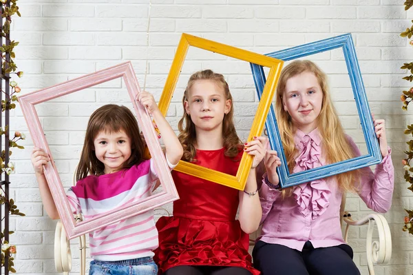 Three girls with frames of paintings — Stock Photo, Image