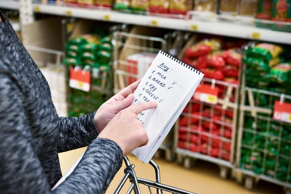 Список покупок в руках женщины в супермаркете — стоковое фото