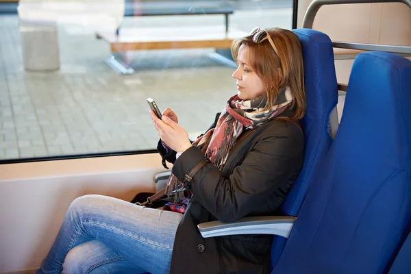 Vrouw met telefoon zitten in de trein op treinstation — Stockfoto
