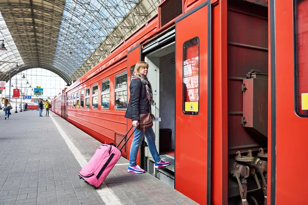 Kvinnelig turist med koffert sitter på toget på jernbanestasjonen – stockfoto
