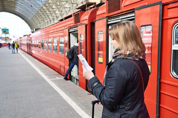 La donna vicino al treno controlla il suo biglietto in stazione — Foto Stock