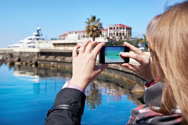 Meisje foto's op mobiele telefoon kust en pier — Stockfoto