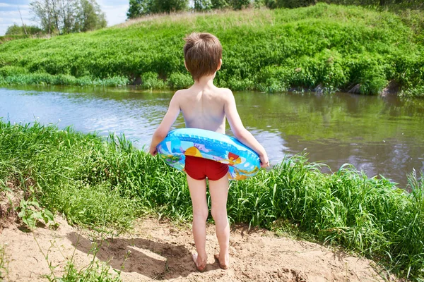 Niño con boya salvavidas de juguete para nadar cerca del río —  Fotos de Stock