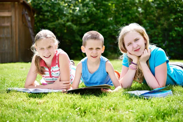 Amici bambini lettura libro outdoori su erba — Foto Stock