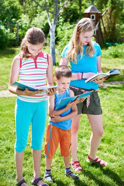 Vrienden kinderen lezen boeken outdoorson gras — Stockfoto