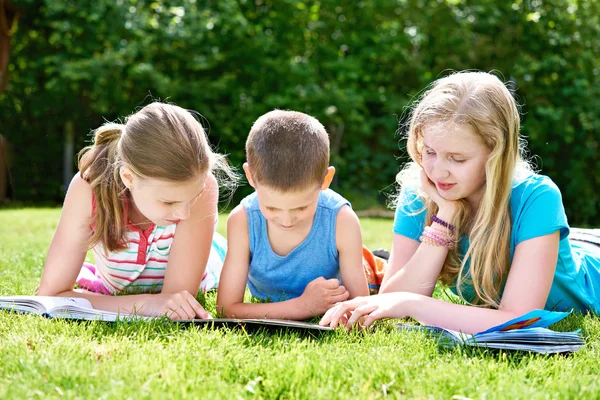 Friends children reading books outdoori on grass Royalty Free Stock Photos