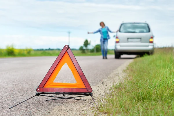 Segno di emergenza e donna in attesa di aiuto vicino alla sua auto — Foto Stock