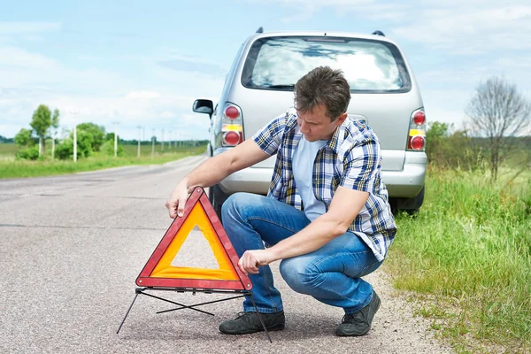 Homme installant un panneau d'urgence sur la route près de sa voiture — Photo