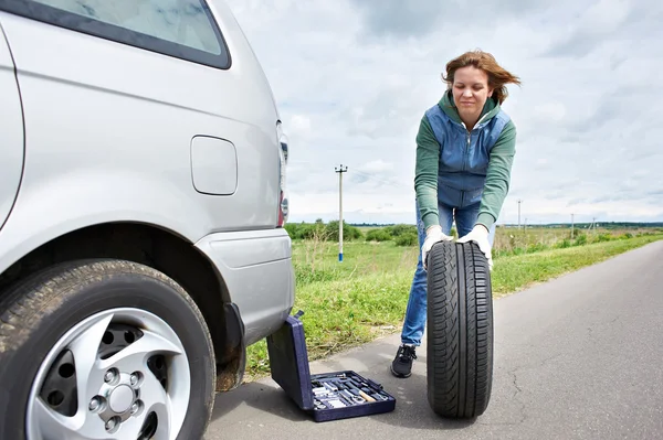 Mujer cambiante rueda de coche — Foto de Stock