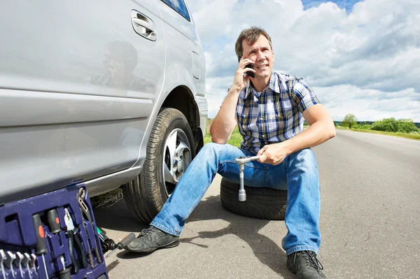 Man met telefoon eist in dienst van reservewiel auto — Stockfoto