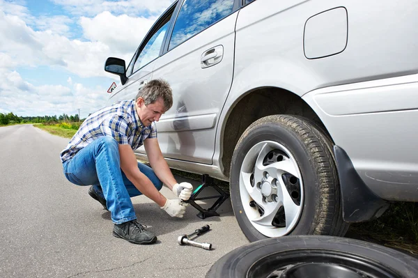 Man changing a spare tire of car Stock Picture