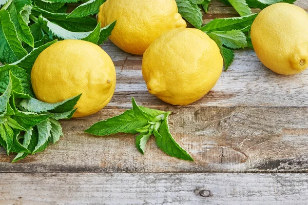 Citrons avec feuilles de menthe sur table en bois — Photo