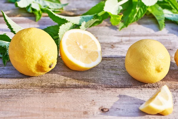 Zitronen mit Minzblättern auf Holztisch — Stockfoto
