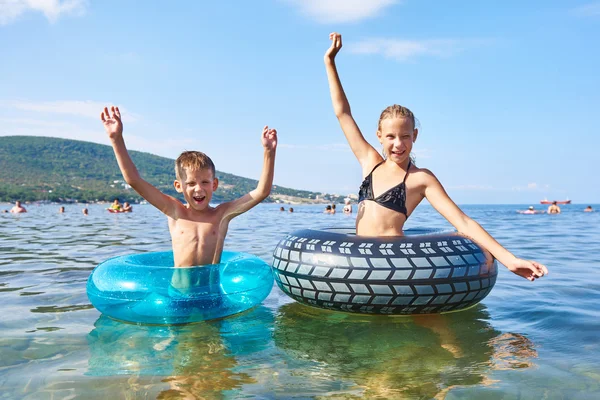 Junge und Mädchen schwimmen mit Spielzeug-Rettungsringe — Stockfoto