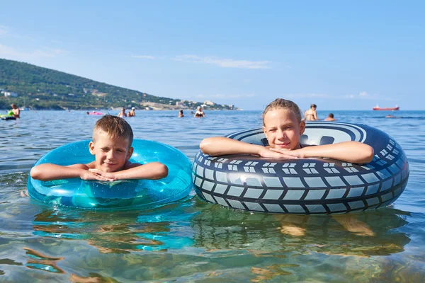 Boy and girl swimming with toy lifebuoys — Stock Photo, Image