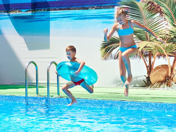 Fille et garçon sautant dans la piscine de la station — Photo