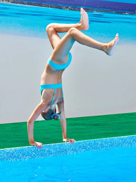 Sportlerin steht auf Händen, um ins Wasser zu springen — Stockfoto