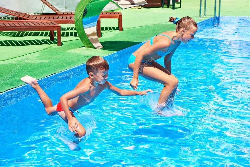 Mädchen und Junge springen in Resort-Pool.