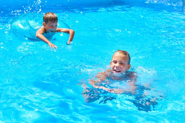 Дівчинка і хлопчик плавають у курортному басейні — стокове фото