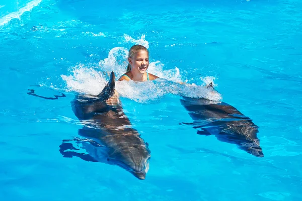 Girl swims with dolphins in pool — Stock Photo, Image