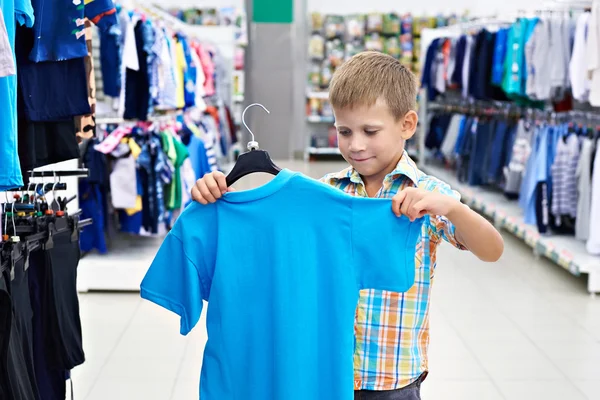 Niño elige camisa en tienda de ropa — Foto de Stock