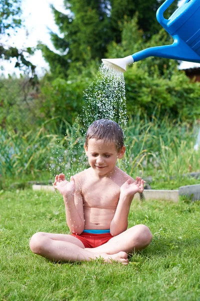 Pieni poika kaataa vettä kastelukannusta — kuvapankkivalokuva