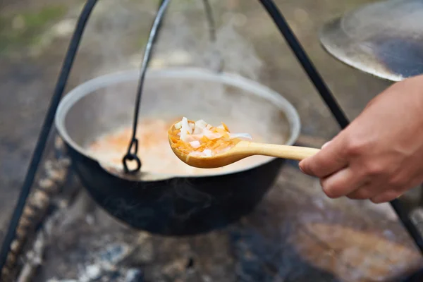 Ξύλινο κουτάλι με το φαγητό πάνω από φωτιά στο χαράτσι — Φωτογραφία Αρχείου