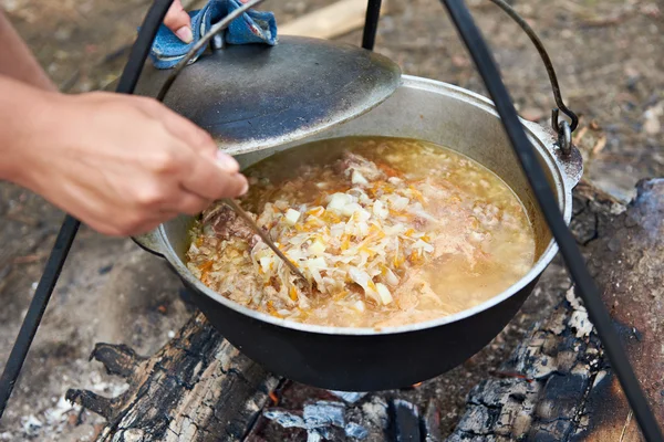 Cooking soup over campfire in hike — Stock Photo, Image