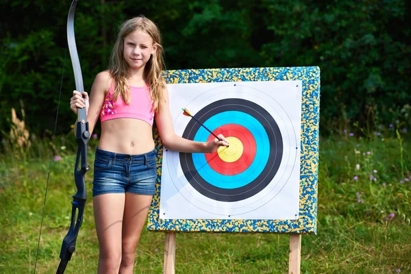Девушка-подросток с луком и стрелами рядом с целью — стоковое фото