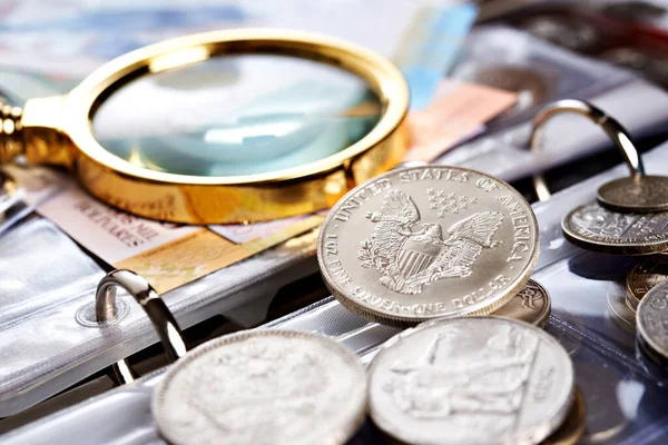 Man numismatist examines coin with magnifying glass Stock Photo by