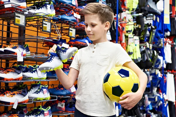 Boy with a ball and boots in a football clothing store