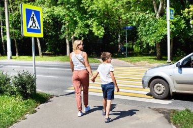 Mother and child walk on pedestrian crossing clipart