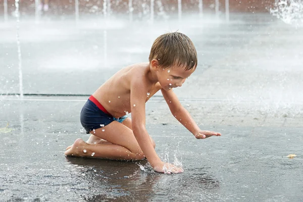 Glückliches Kind, das in einem Brunnen spielt — Stockfoto