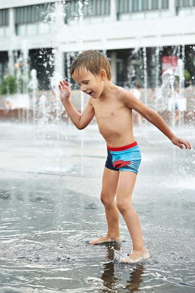 Gelukkig kind spelen in een fontein — Stockfoto