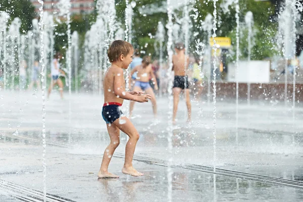 Glückliches Kind, das in einem Brunnen spielt — Stockfoto