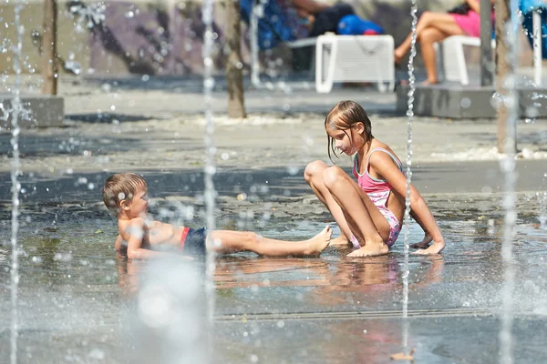 Niños jugando en charco en clima cálido — Foto de Stock