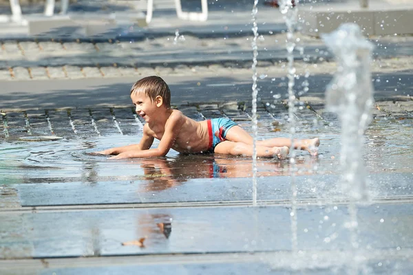 Menino brincando com água em uma poça — Fotografia de Stock