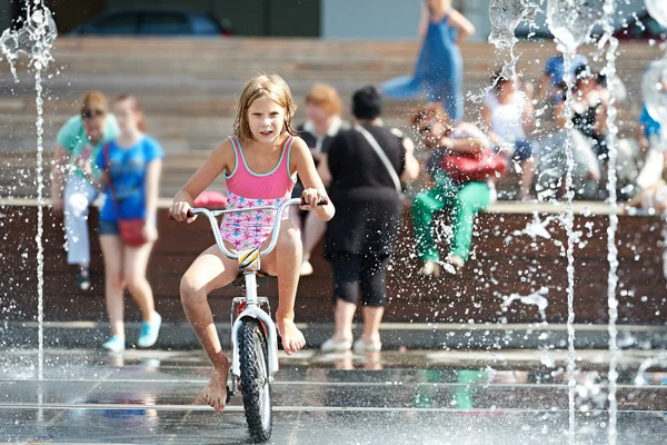 Menina monta sua bicicleta entre fontes — Fotografia de Stock