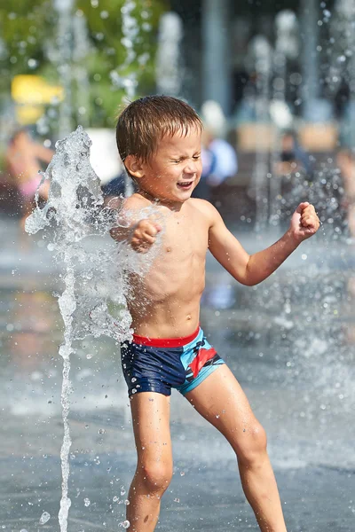 Счастливый ребенок играет в фонтане — стоковое фото