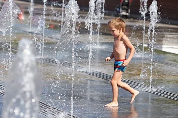 Niño feliz jugando en una fuente — Foto de Stock