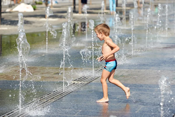 Criança feliz correndo em uma fonte — Fotografia de Stock