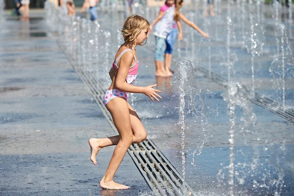 Little girl running among fountains — Stock Photo, Image